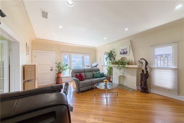 living area featuring a wealth of natural light, visible vents, baseboards, and light wood-style floors