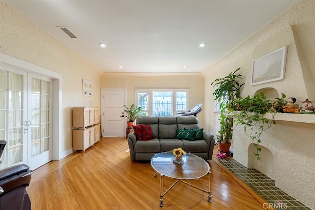 living area featuring visible vents, light wood-style floors, recessed lighting, and a textured wall