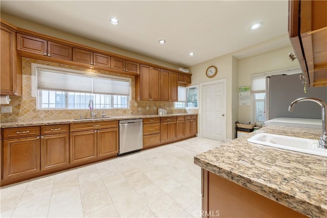 kitchen with brown cabinetry, a sink, stainless steel appliances, and tasteful backsplash