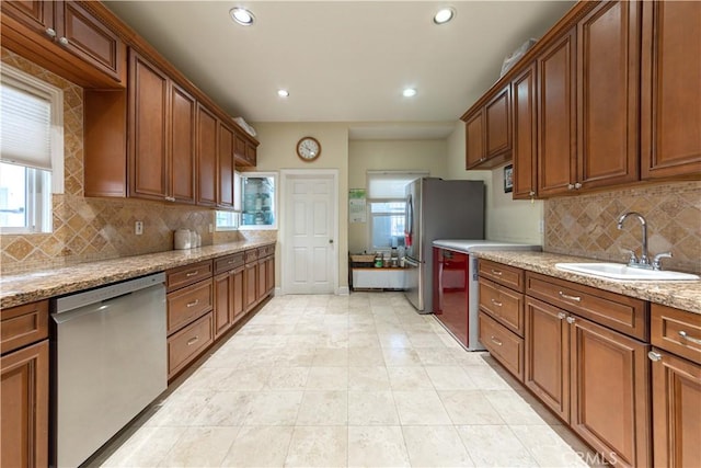 kitchen featuring recessed lighting, light stone countertops, a sink, decorative backsplash, and dishwasher