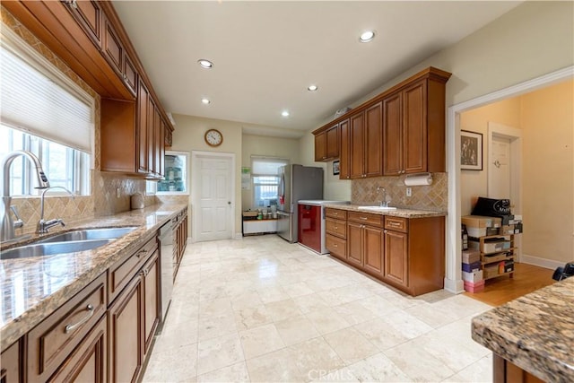 kitchen with light stone counters, a wealth of natural light, recessed lighting, and a sink