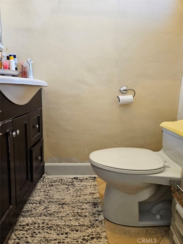 bathroom with toilet, vanity, and baseboards