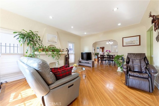 living area featuring recessed lighting, arched walkways, an inviting chandelier, and light wood-style floors