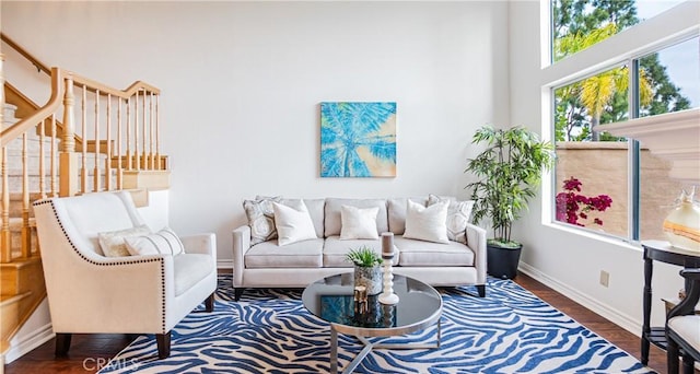 living room with stairway, baseboards, a high ceiling, and wood finished floors