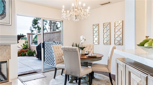 dining space featuring visible vents, wood finished floors, and an inviting chandelier
