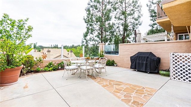 view of patio featuring fence, outdoor dining space, and a grill