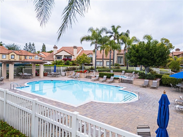 community pool with a patio area and fence