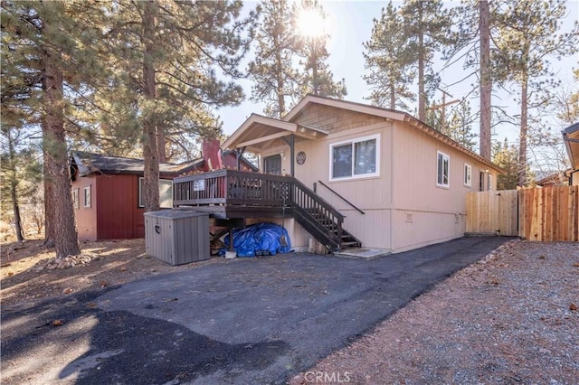 view of front of house featuring an outdoor structure, stairs, a deck, a shed, and fence