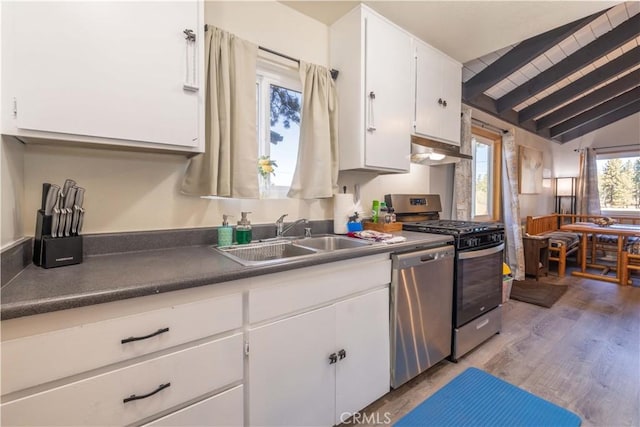 kitchen featuring vaulted ceiling with beams, stainless steel appliances, under cabinet range hood, white cabinets, and a sink