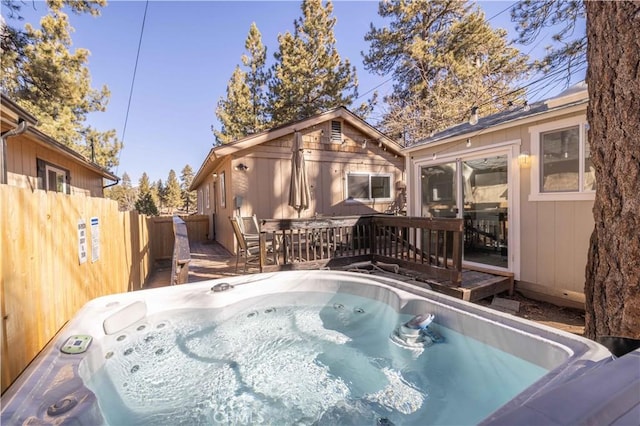 back of property with a deck, fence, and a hot tub