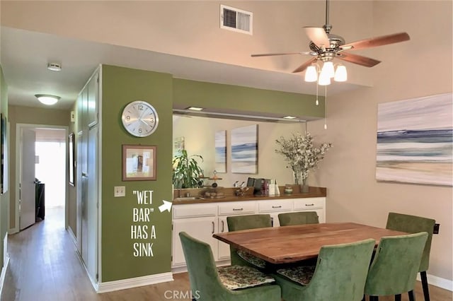dining area with baseboards, a ceiling fan, wood finished floors, and visible vents