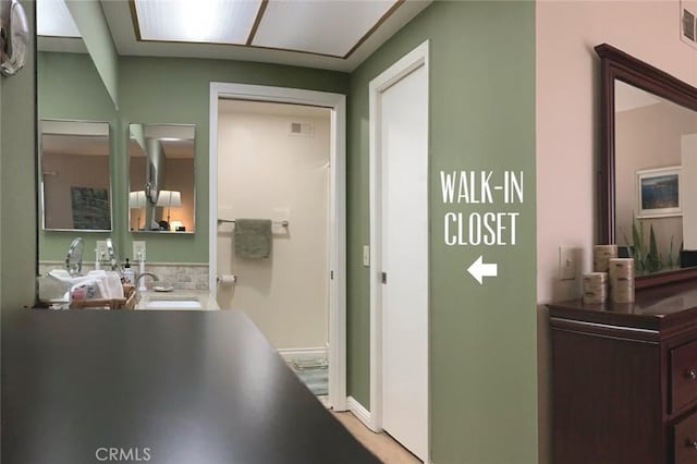 hall with baseboards, visible vents, and a sink