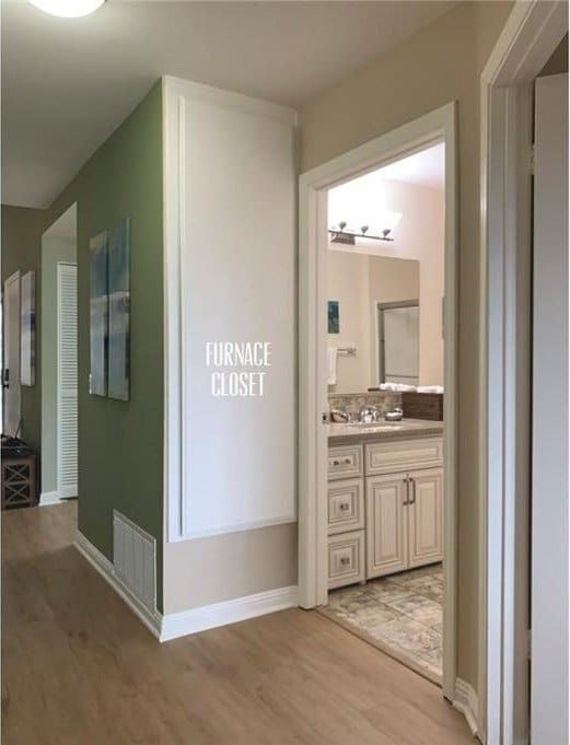 corridor featuring a sink, baseboards, light wood-style flooring, and visible vents