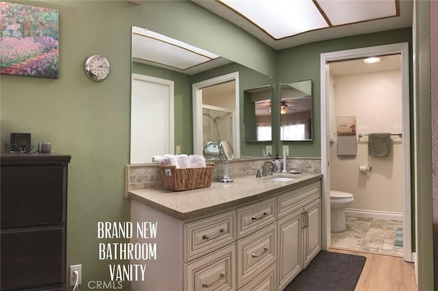 full bath featuring vanity, decorative backsplash, wood finished floors, toilet, and baseboards