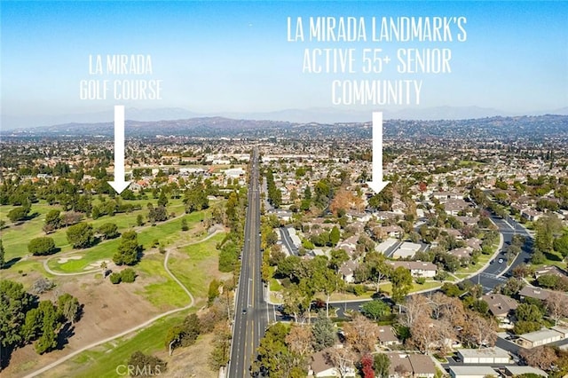 drone / aerial view with view of golf course, a mountain view, and a residential view