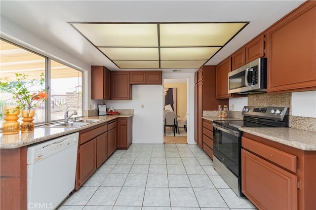 578 Vista Rambla, Walnut, CA 91789 - kitchen featuring stainless steel appliances, a sink, brown cabinetry, light tile patterned flooring, and light stone counters