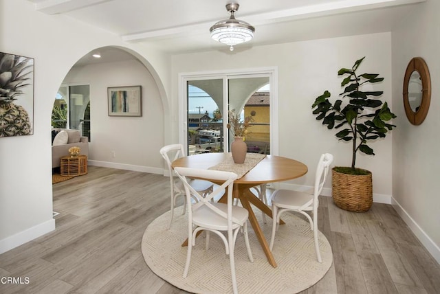 dining room with beamed ceiling, light wood finished floors, and baseboards