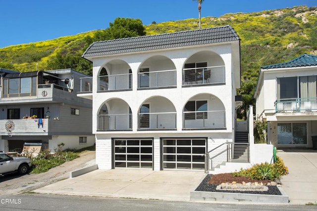view of property with a mountain view, driveway, a garage, and stairway