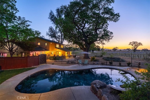 pool at dusk with fence, a patio area, and a fenced in pool