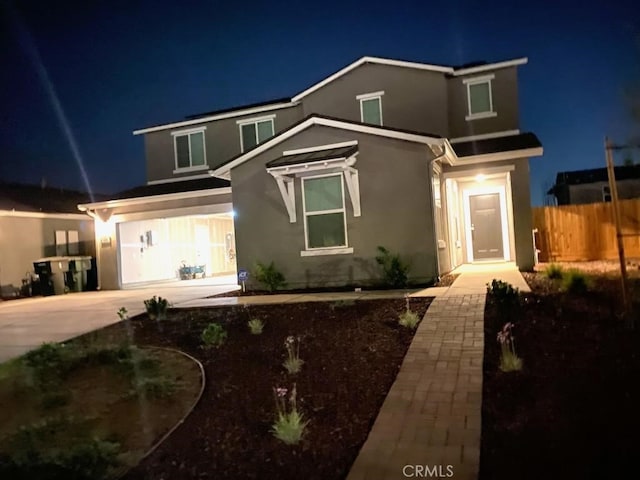 traditional home featuring stucco siding, an attached garage, fence, and driveway