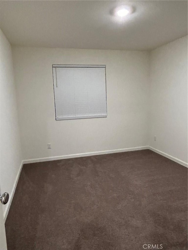 empty room with dark carpet and baseboards