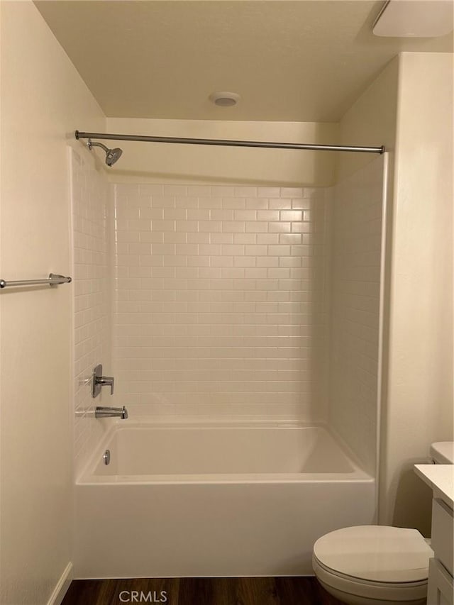 bathroom featuring vanity, toilet, wood finished floors, and shower / washtub combination