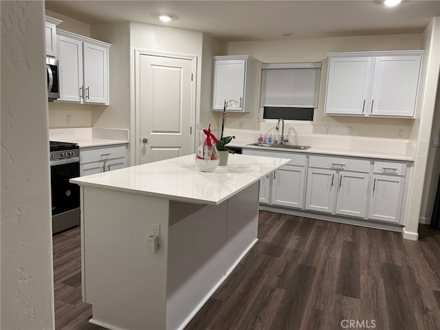 kitchen featuring appliances with stainless steel finishes, a sink, light countertops, white cabinets, and dark wood-style floors