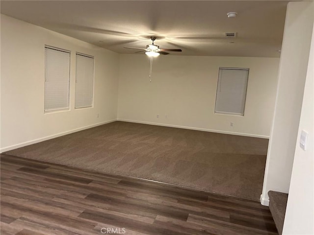 unfurnished room featuring baseboards, a ceiling fan, dark colored carpet, and visible vents