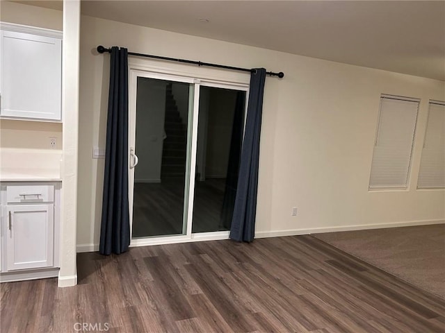 unfurnished room featuring baseboards and dark wood-style floors
