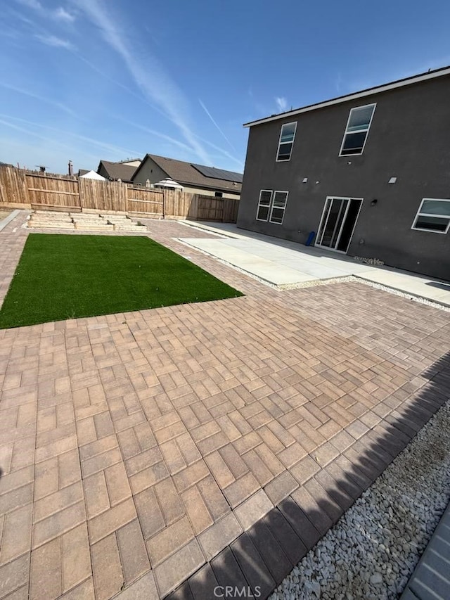 rear view of house featuring a fenced backyard, a patio, and a yard
