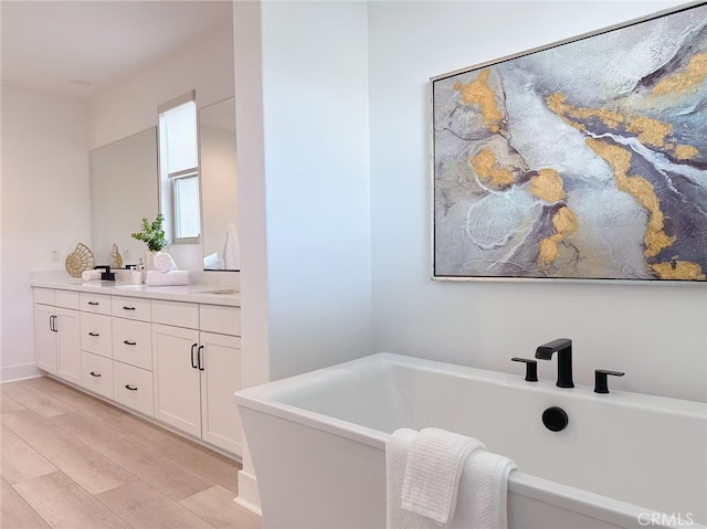 full bath with vanity, a soaking tub, and wood finished floors