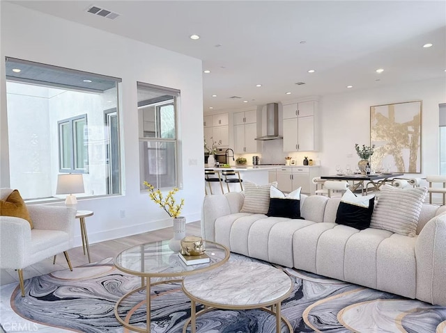 living room featuring recessed lighting, baseboards, visible vents, and light wood-style flooring