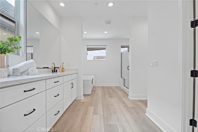 full bathroom featuring visible vents, a shower stall, wood finished floors, vanity, and baseboards