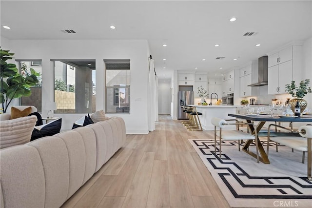 living room featuring light wood-type flooring, recessed lighting, and visible vents