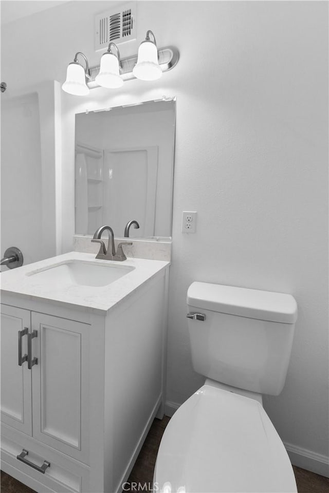 bathroom with toilet, baseboards, visible vents, and vanity