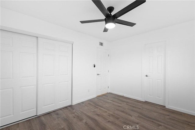 unfurnished bedroom featuring dark wood finished floors, a ceiling fan, baseboards, visible vents, and a closet
