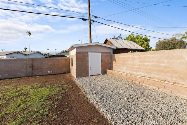 view of yard featuring a fenced backyard, an outdoor structure, and a storage shed