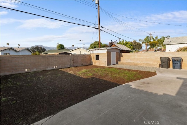 view of yard with a storage unit, a fenced backyard, a patio area, and an outdoor structure