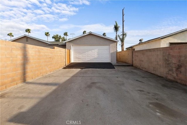 garage featuring fence and concrete driveway
