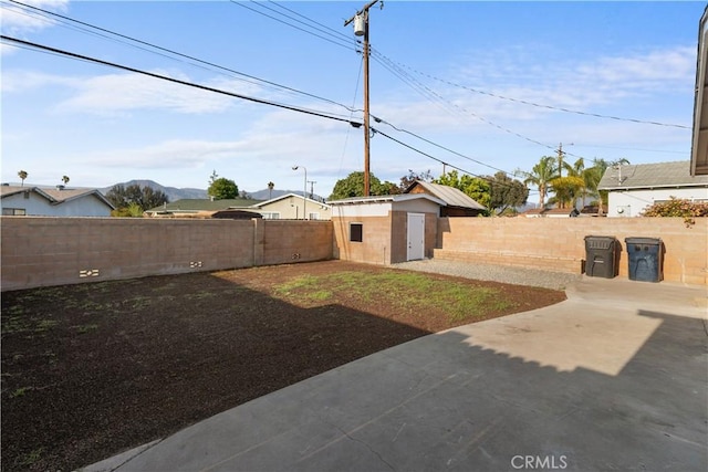view of yard featuring an outdoor structure, a fenced backyard, a patio area, and a shed