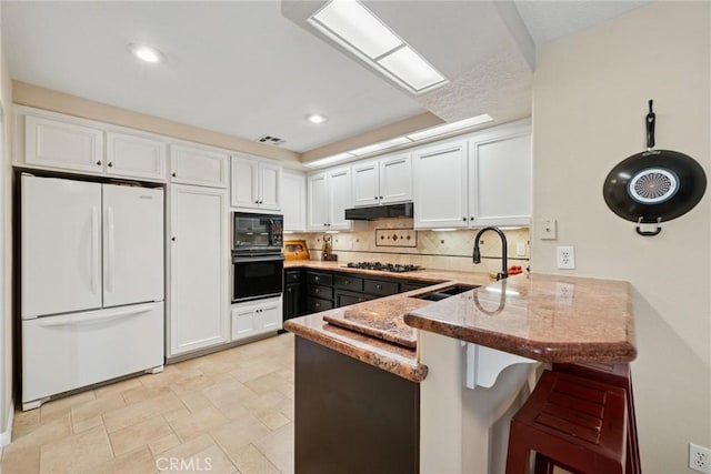 33046 Ocean Rdg, Dana Point, CA 92629 - kitchen featuring freestanding refrigerator, a peninsula, black microwave, under cabinet range hood, and a sink