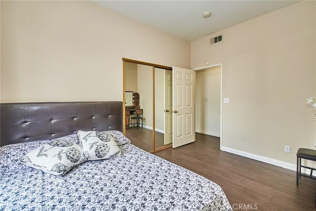 bedroom with baseboards, a closet, wood finished floors, and visible vents