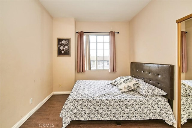 bedroom with dark wood-type flooring and baseboards