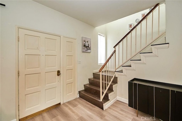 entrance foyer featuring stairway, baseboards, and light wood-type flooring