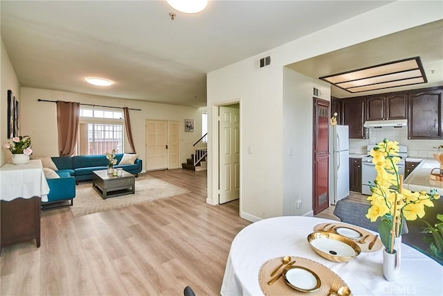 living room featuring light wood finished floors, stairs, and visible vents