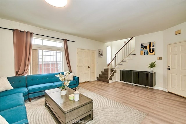 living room featuring baseboards, stairway, and light wood-type flooring