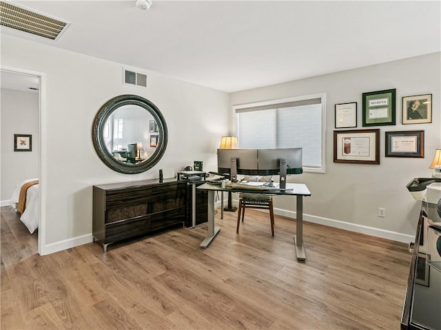 office space featuring baseboards, visible vents, and light wood-style floors
