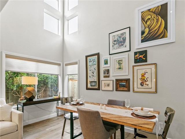 dining area with baseboards, a high ceiling, and wood finished floors