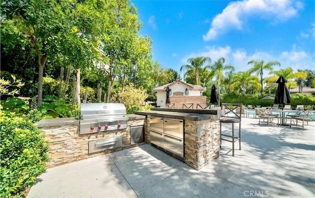view of patio with area for grilling, exterior kitchen, and outdoor wet bar