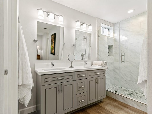 full bath with a sink, a shower stall, and wood finished floors